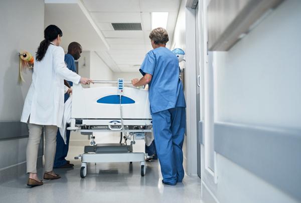 Rearview shot of a medical team pushing a patient down the hallway in a gurney.